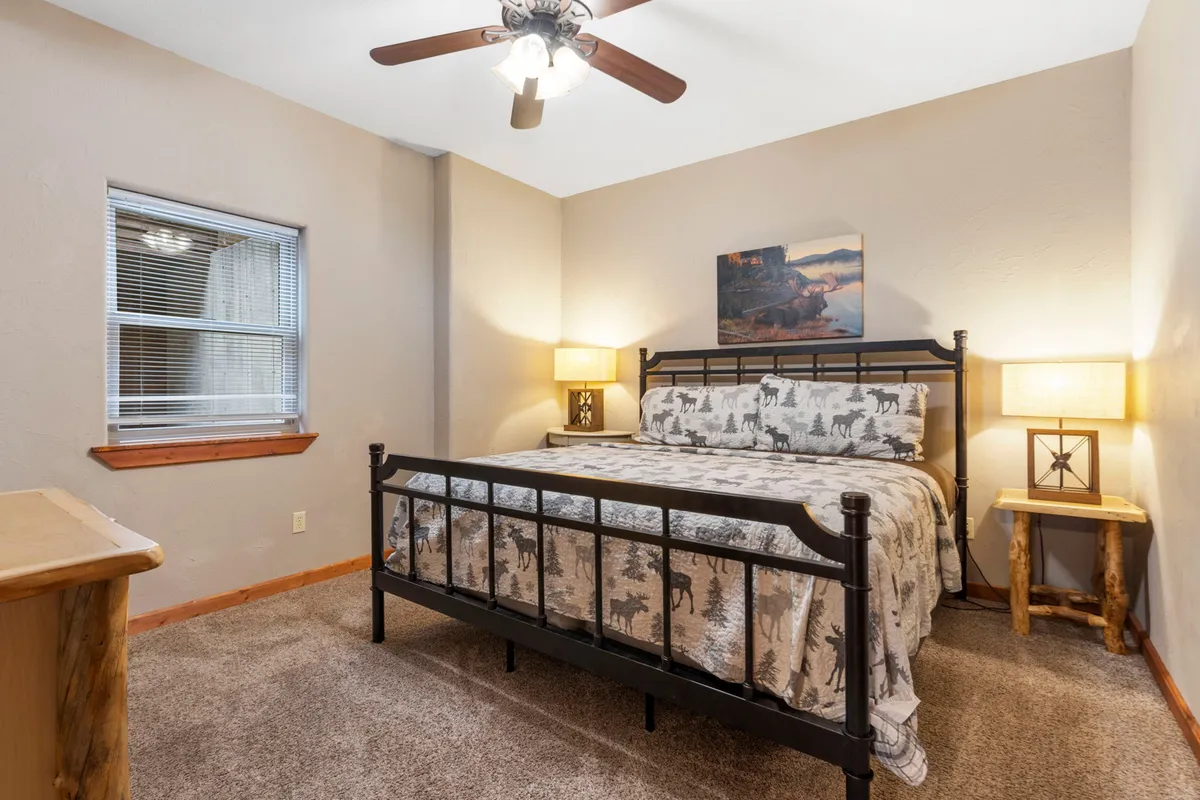 This inviting bedroom features a king-sized bed with patterned bedding, wooden nightstands, and comforting wall art. Soft natural light streams in, contributing to a tranquil and restful atmosphere. The space feels spacious and designed for relaxation, aligning with the idea of a private sleep sanctuary.